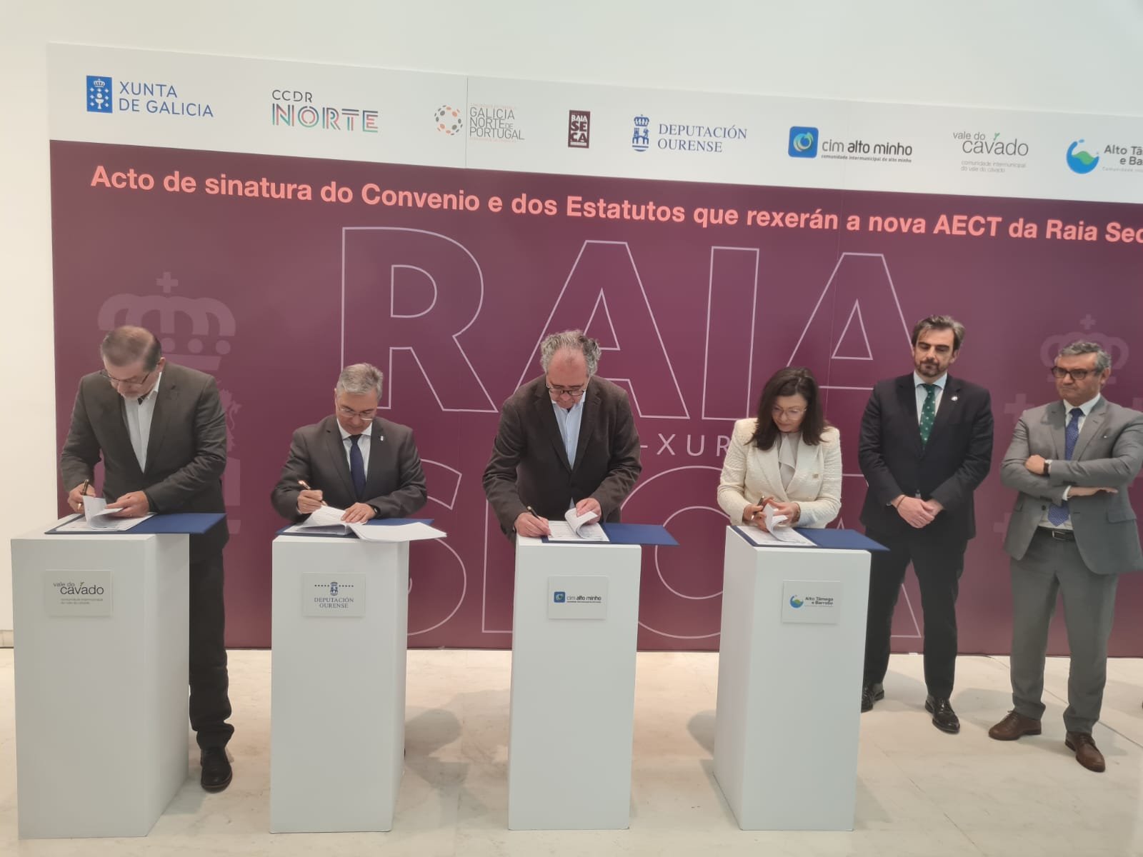 Na foto surgem os representantes das várias entidades envolvidas na criação do AECT a assinar o convénio, dispostos lado a lado, cada um com uma pequena mesa à frente.
