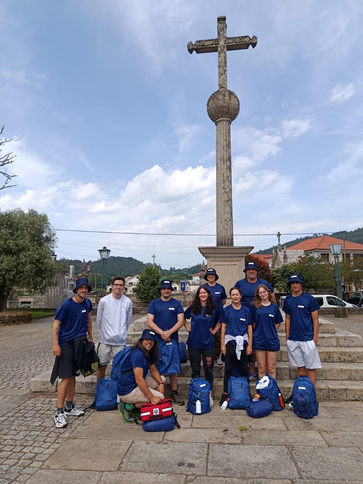 Os participantes da primeira expedição estão junto a um cruzeiro todos com tshirts da mesma cor e chapéu.